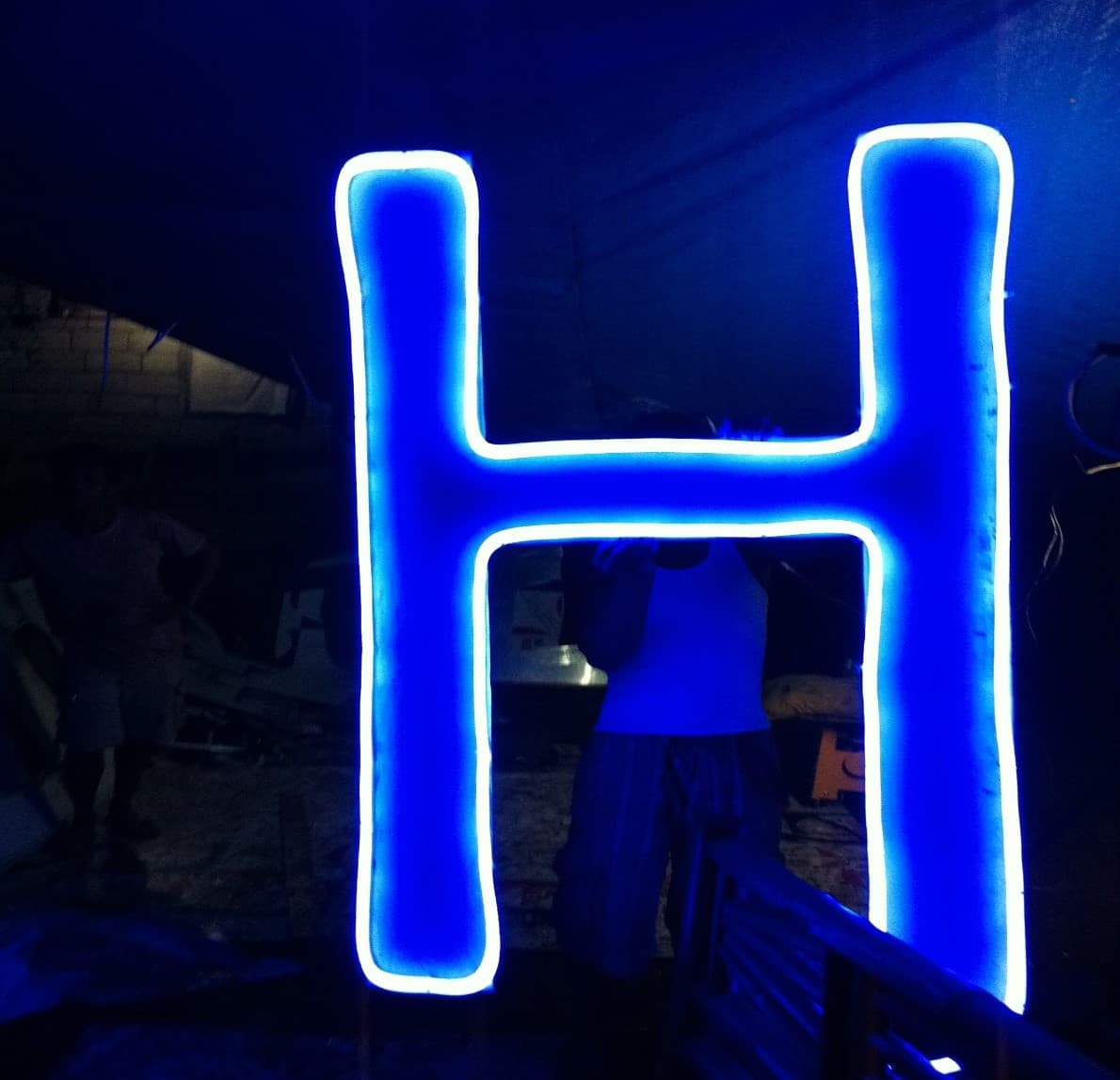 Blue neon channel letter H in fabrication shop
